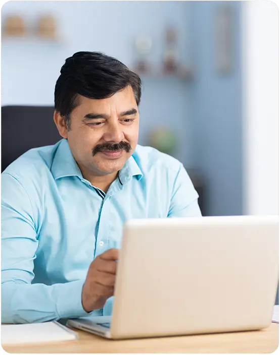 Man sitting at a desk, intently focused on the laptop computer in front of him